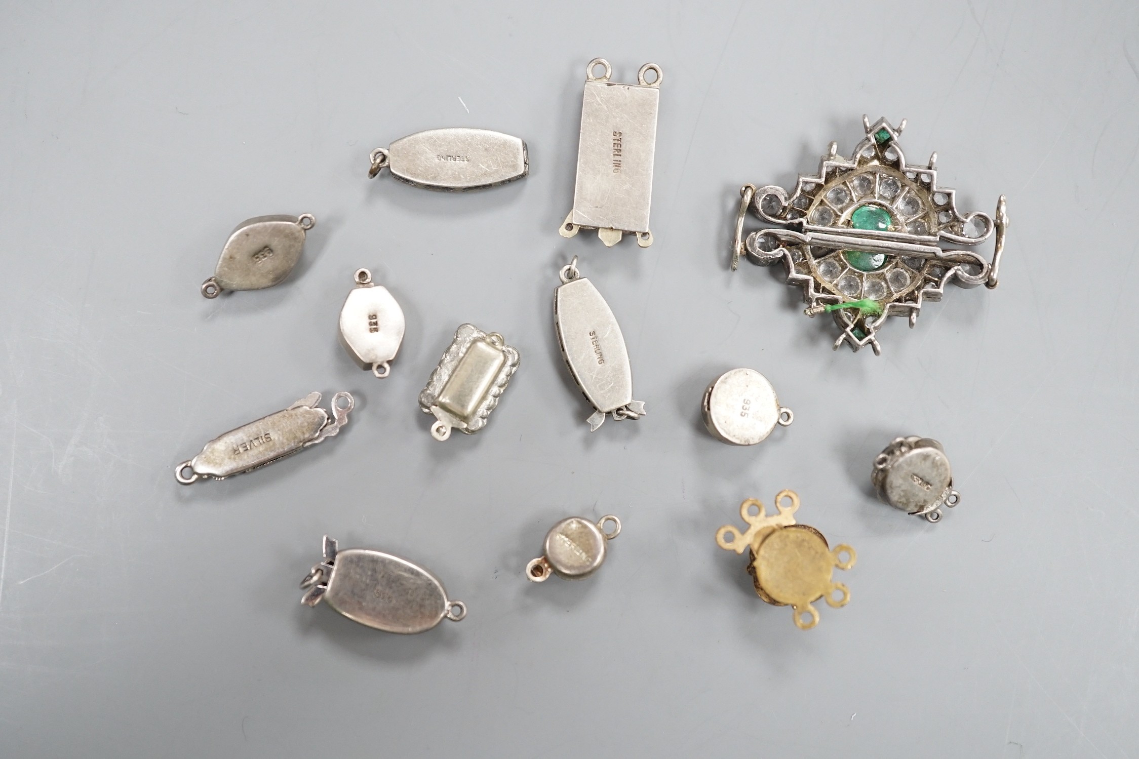A small group of assorted white or base metal and paste set clasps.
